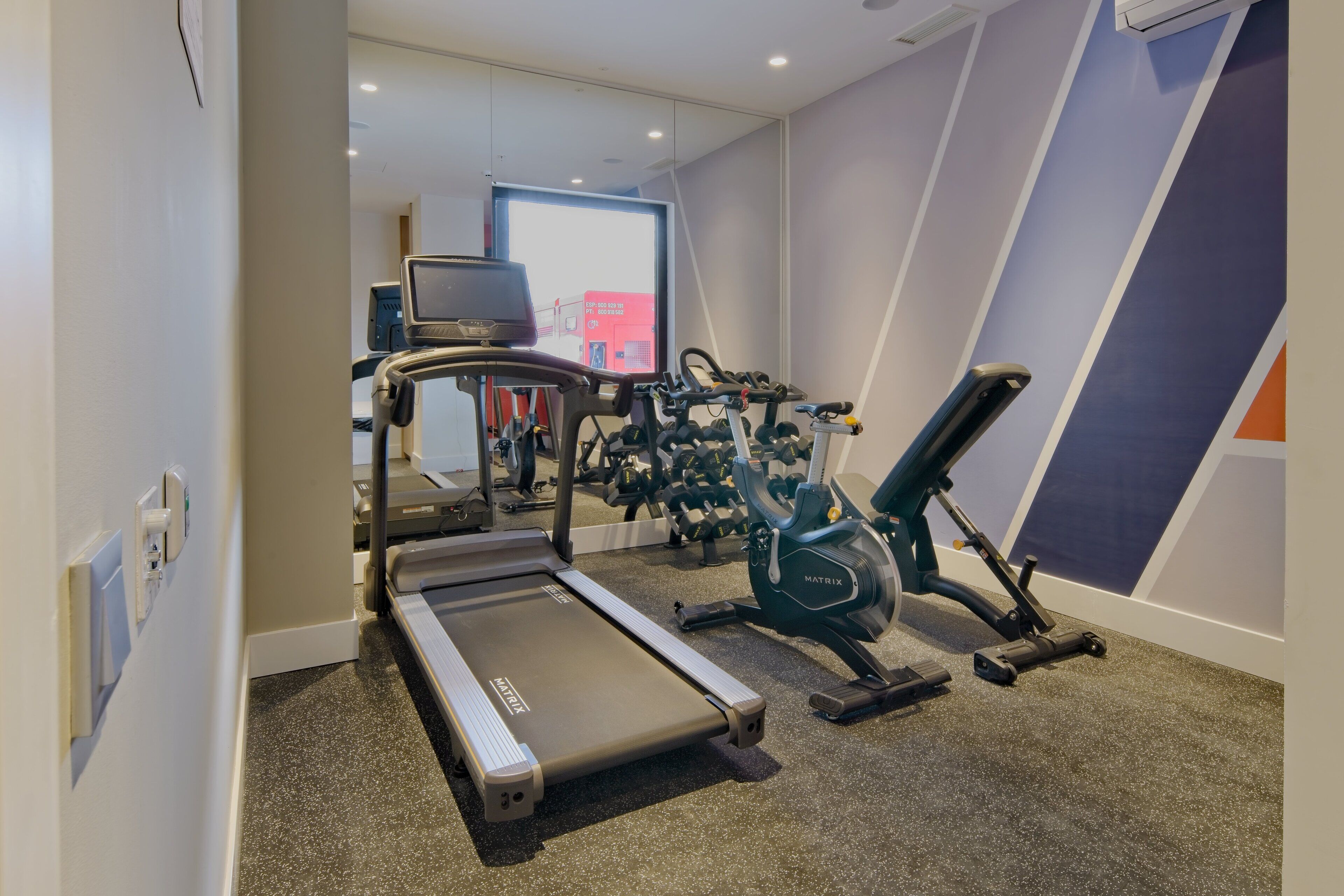 Un gimnasio con cinta de correr, elíptica y máquinas de pesas.