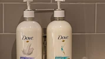 Twee Dove douche- en shampoobotten op een badkamerplank.