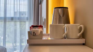 A coffee maker, two white mugs, and a tissue box on a tray near a window.