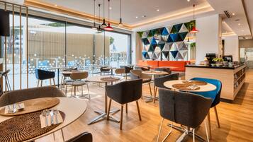 Un restaurante moderno con mesas redondas, sillas y una zona de bar.