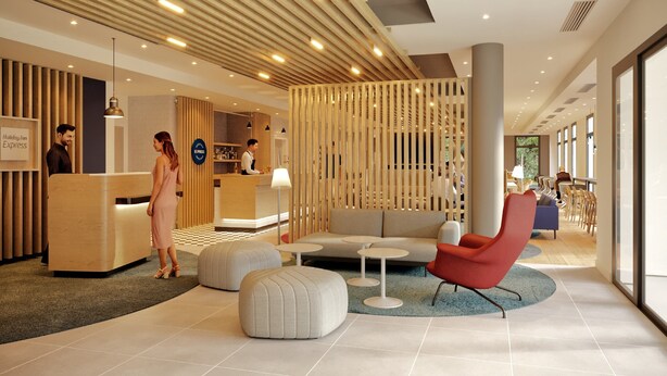 Un hall d’hôtel moderne avec un comptoir d’accueil, un espace salon et une grande fenêtre.