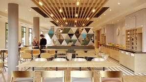 Un restaurant moderne doté d’un comptoir central, de plusieurs espaces de restauration et d’un décor mural aux motifs géométriques.