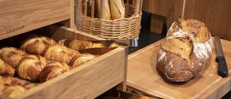 A bakery display with various baked goods, including croissants and bread, arranged in wooden boxes and baskets.