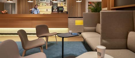 Un área de estar moderna con asientos, un bar y una máquina de café.