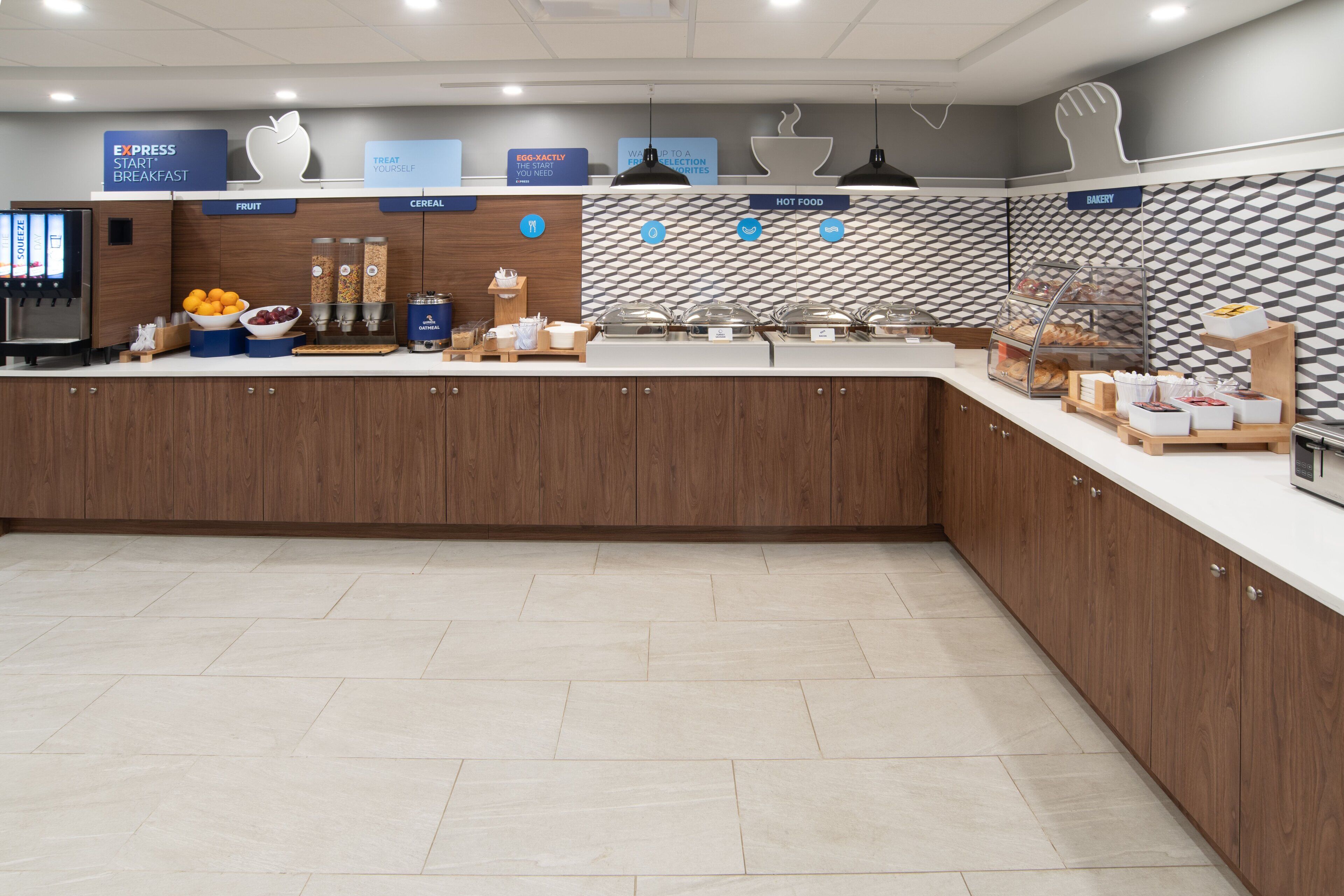 A modern breakfast area with labeled sections for fruit, cereal, hot food, and bakery.