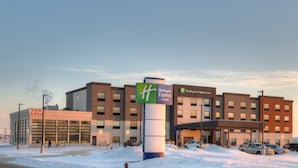 A Holiday Inn Express & Suites building with a large sign, multiple parking spaces, and a snow-covered ground. - Holiday Inn Express and Suites Moose Jaw by IHG (Moose Jaw)