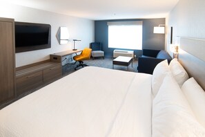 Una habitación de hotel con una cama grande, un escritorio, una silla, un televisor y una ventana.