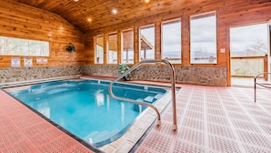 An indoor swimming pool with wooden walls and a stone accent wall. - NEW listing! INDOOR POOL, panoramic views, & game room - 15 min to Pigeon Forge (Sevierville)