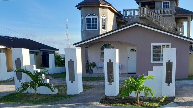 A two-story house with a balcony, a small porch, and a front door. - Vacation Home Rental (Florence Hall Village)