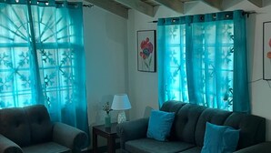 A living room with a sofa, armchair, and ottoman, a small table with a lamp, and a painting on the wall. - Vacation Home Rental (Florence Hall Village)
