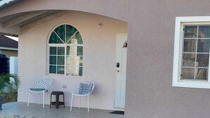 A house with a curved facade, a large arched window, and a door with a keypad lock. There are two white chairs outside. - Vacation Home Rental (Florence Hall Village)