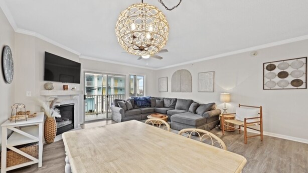 Ein stilvolles Wohnzimmer mit Esstisch aus Holz, grauem Sofa und einer dekorativen Deckenleuchte.
