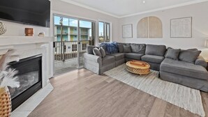 Ein Wohnzimmer mit Kamin, grauem Ecksofa und Deckenventilator.