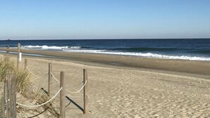 Ein Sandstrand mit einer Holzlattenzaun und Seilabsperrung.