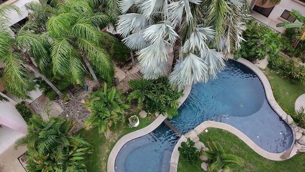 An aerial view of a resort with multiple swimming pools surrounded by lush greenery and palm trees.