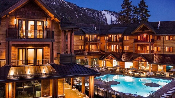 A lodge with multiple guest rooms, a pool area, and a mountain backdrop.