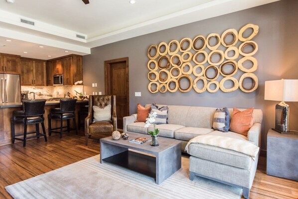 Un salon moderne avec un canapé gris, une table basse et un élément de décoration circulaire en bois fixé au mur.