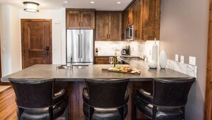 A modern kitchen with dark wood cabinets, stainless steel appliances, and a marble countertop.