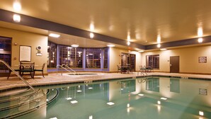 An indoor swimming pool with clear water, surrounded by a tiled deck and equipped with poolside chairs and tables. - Free Breakfast Buffet. Pool, Hot Tub & Gym Access! (Novi)