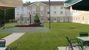 A courtyard with a basketball court, outdoor seating area, and a building with multiple windows.