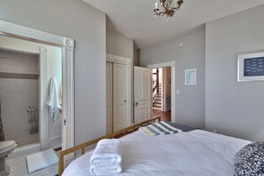 Une chambre avec un lit, une salle de bain avec une douche et un escalier menant à un autre étage.