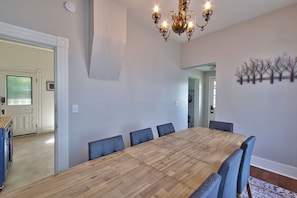 Un coin repas comprenant une table en bois et six chaises, un lustre et une œuvre d’art accrochée au mur.
