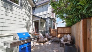 Un patio trasero con una parrilla, mobiliario exterior y una valla de madera.
