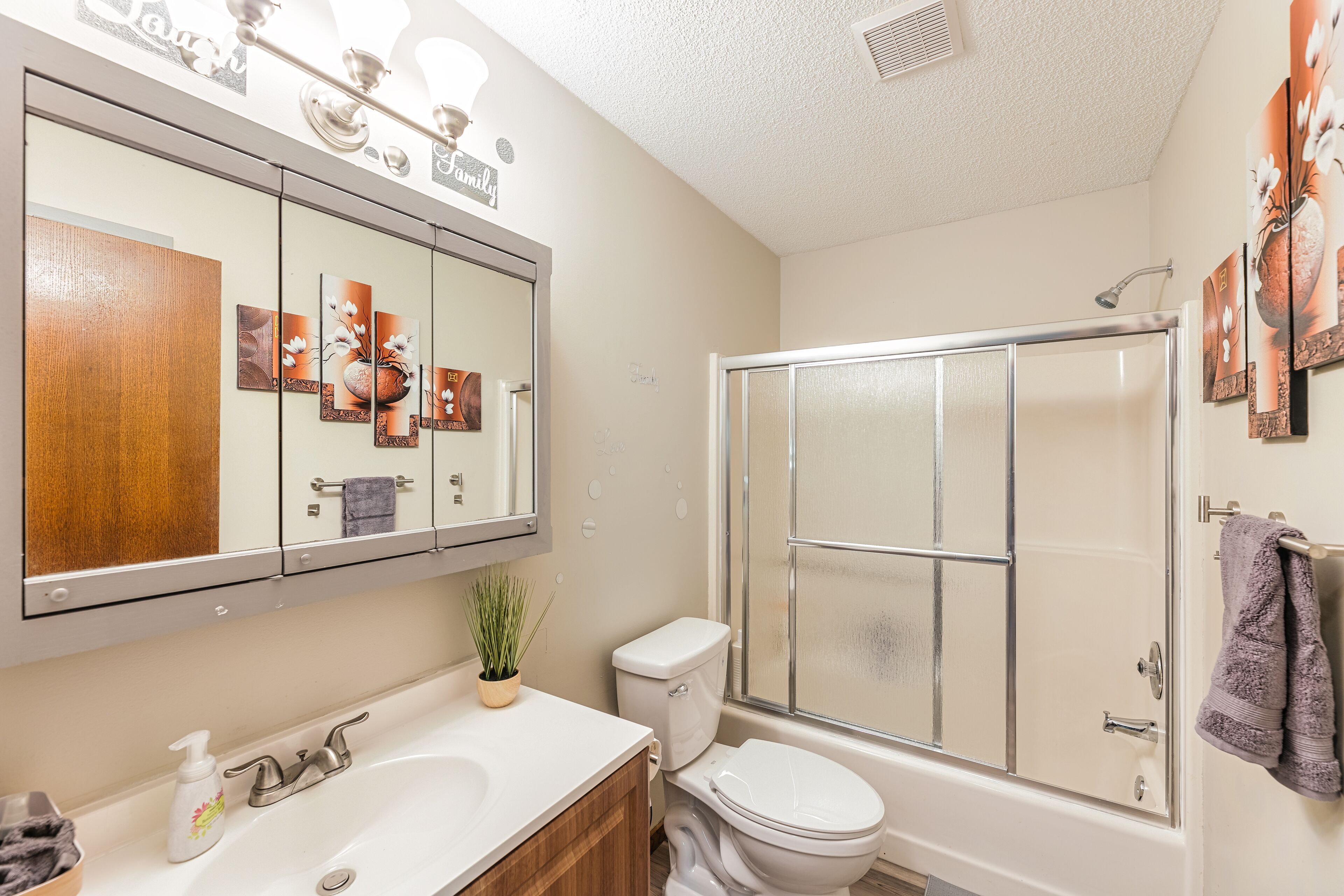 Une salle de bain avec un grand miroir, des toilettes, une douche et un lavabo.