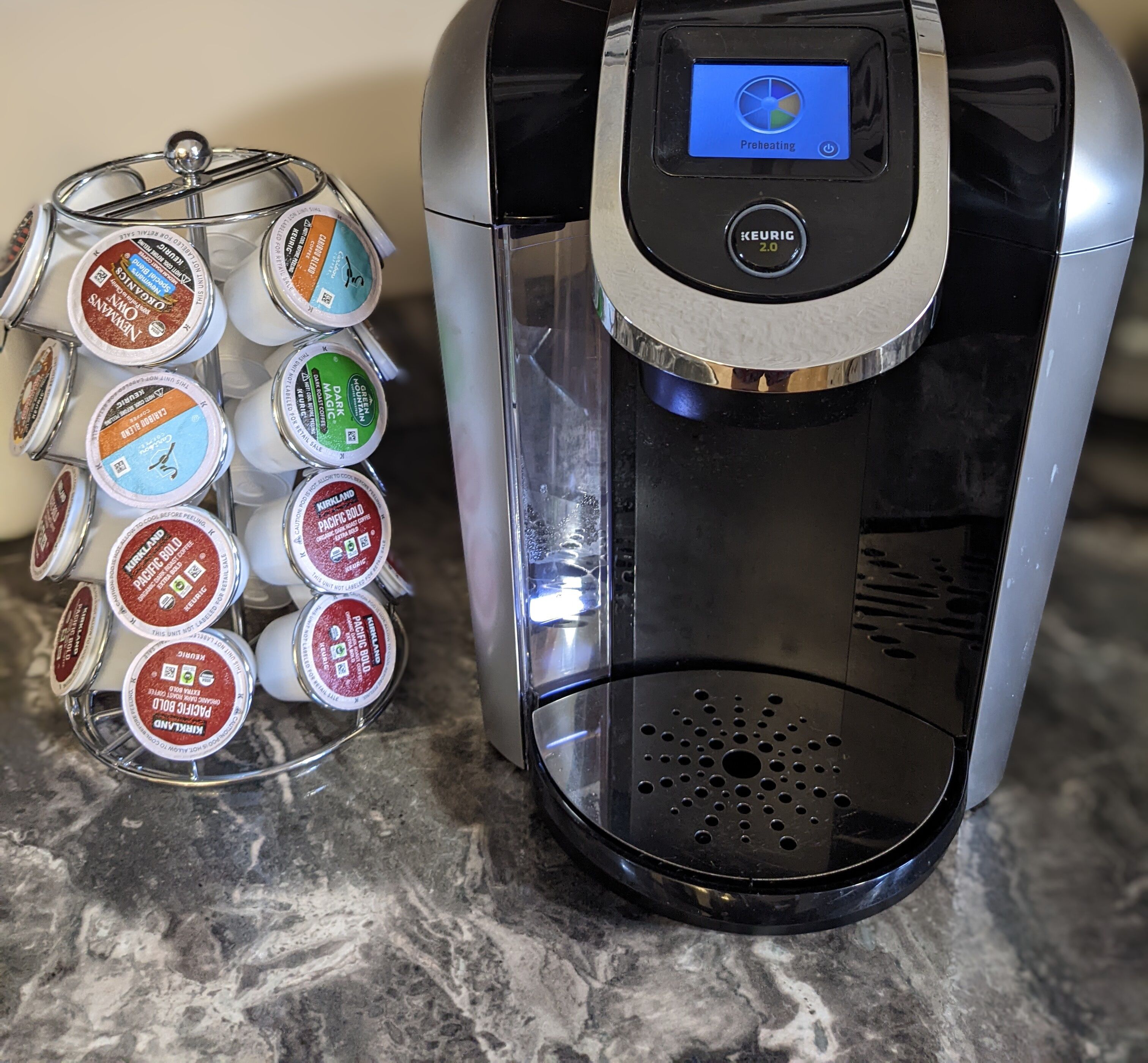 Eine Kaffeemaschine von Keurig mit Glasbehälter und einem Vorrat an Kaffeekapseln.