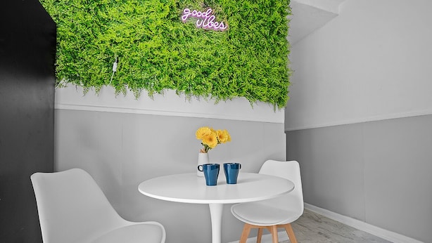 Un tavolo bianco con due sedie, un vaso con fiori gialli e due tazze blu.