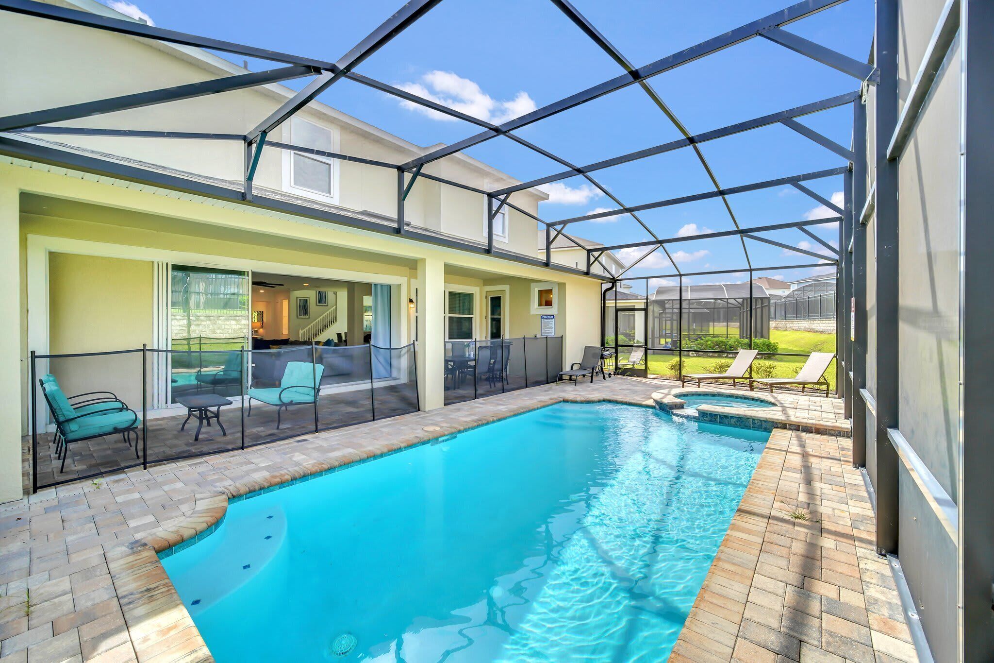 A swimming pool with a covered patio area, outdoor seating, and a view of the surrounding landscape.
