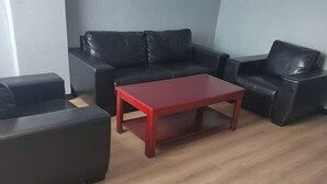 Ein Wohnzimmer mit einem roten Couchtisch, schwarzen Ledersofas und Holzboden.