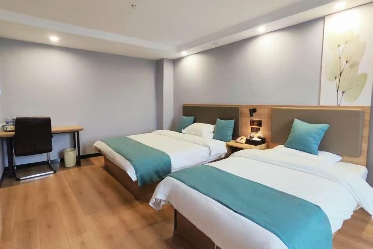 Habitación de hotel con dos camas, un escritorio y una silla.