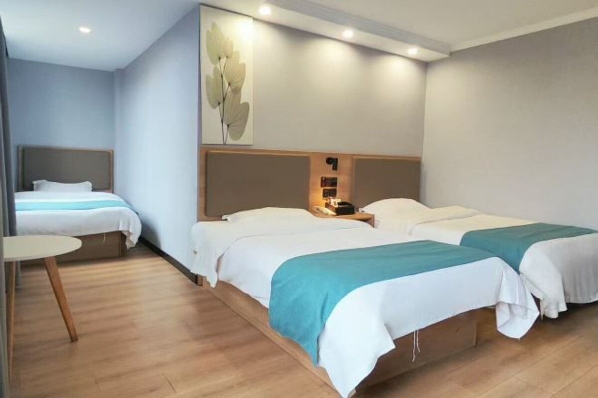 Een hotelkamer met twee bedden, een tafeltje en een wandlamp.