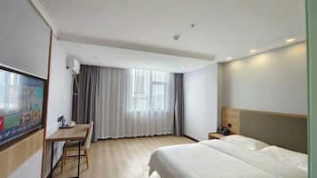 A hotel room with a bed, a desk, a chair, a television, and a window with curtains.