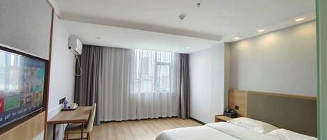 Una habitación de hotel con cama, escritorio, silla, televisor y ventana con cortinas.