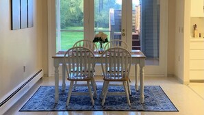 Un espace repas comprenant une table et des chaises, un lustre et une vue à travers des portes vitrées.