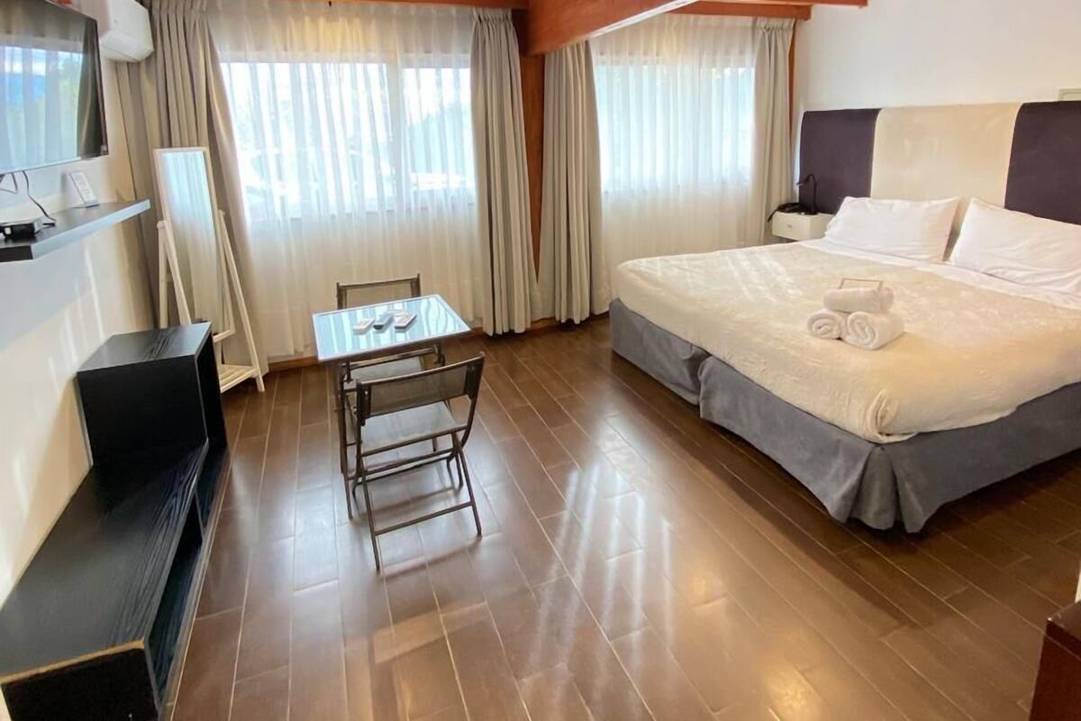 A hotel room with a bed, a desk, and a television.