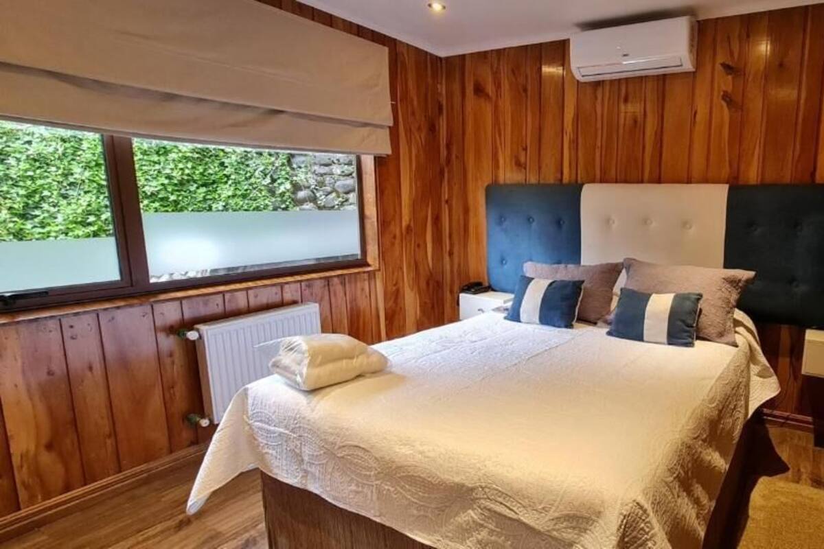 A wooden-paneled bedroom with a bed, bedside tables, and a window.