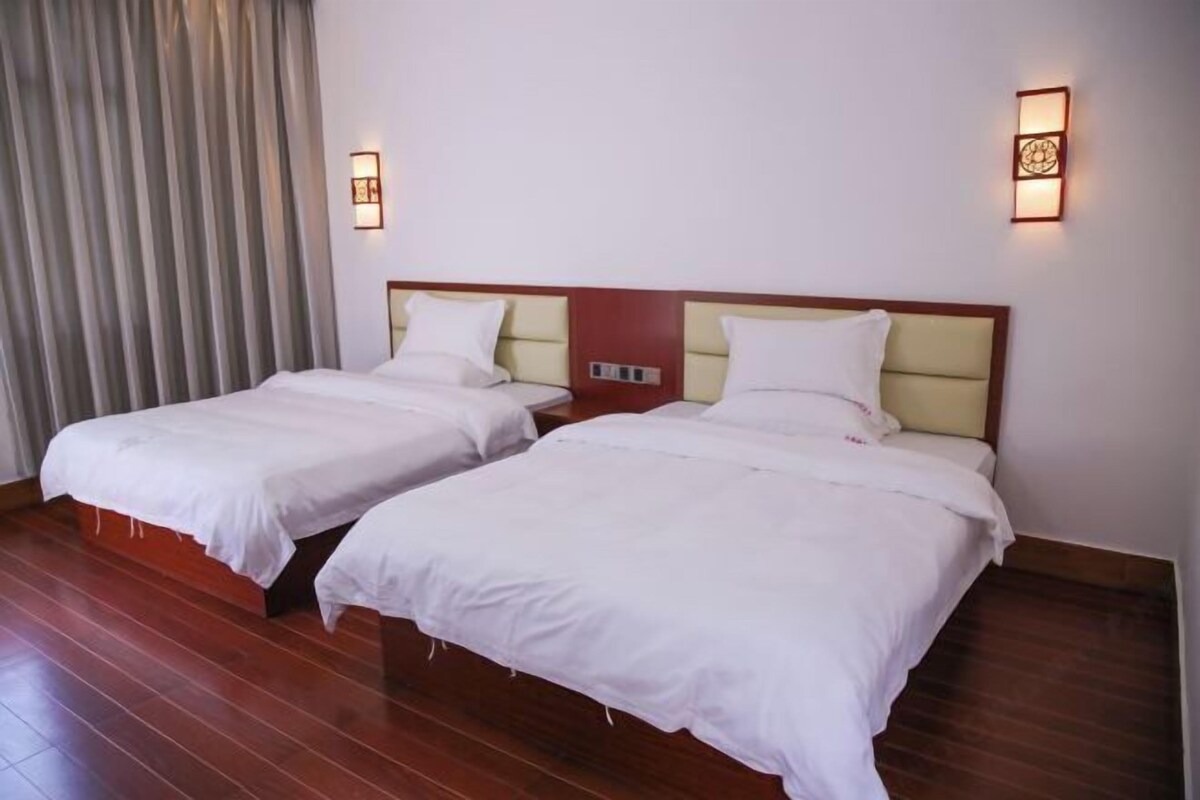 Two single beds with wooden headboards and white bedding in a hotel room.