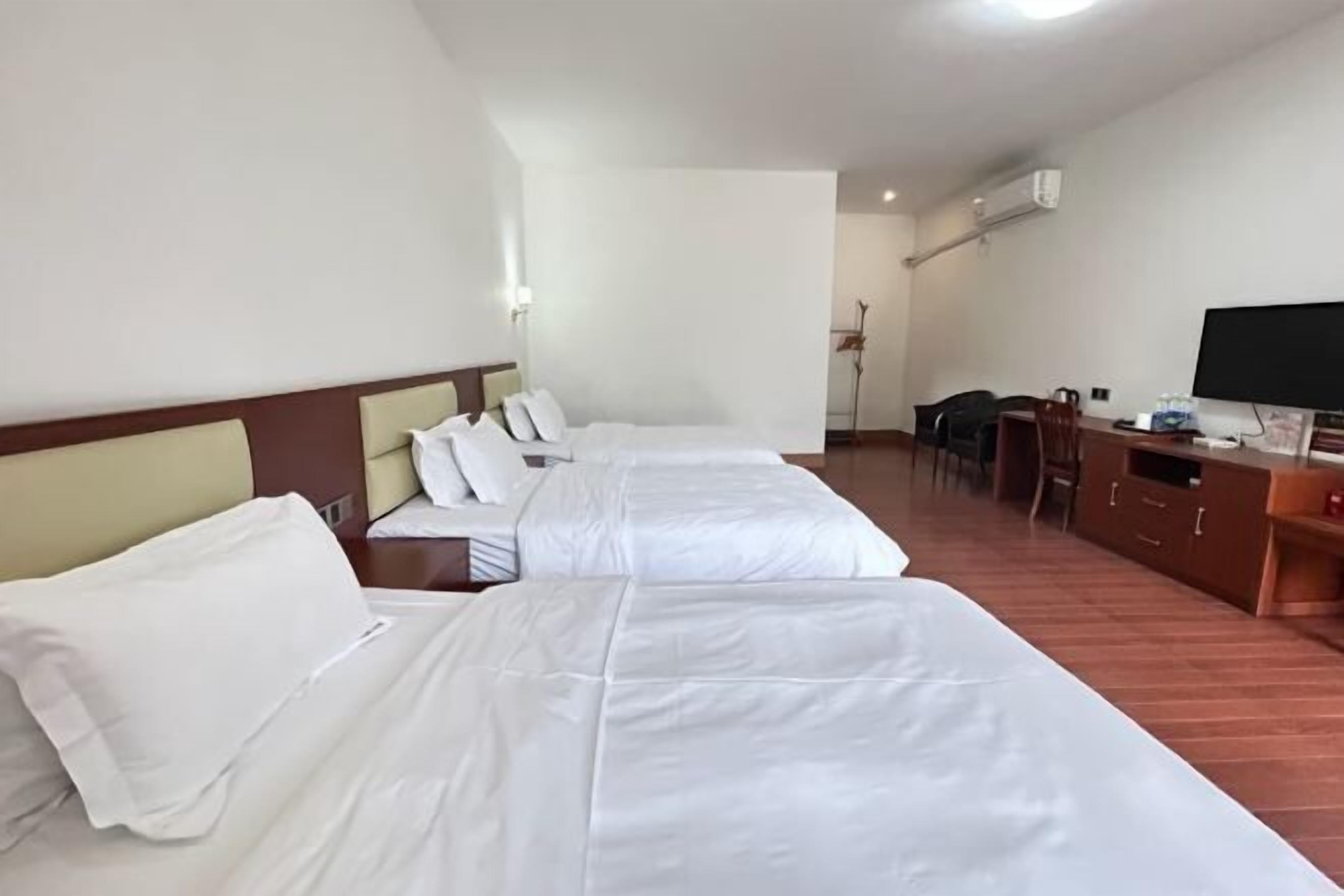 Ein Hotelzimmer mit zwei Betten, einem Schreibtisch, einem Sessel und einem Fernseher.