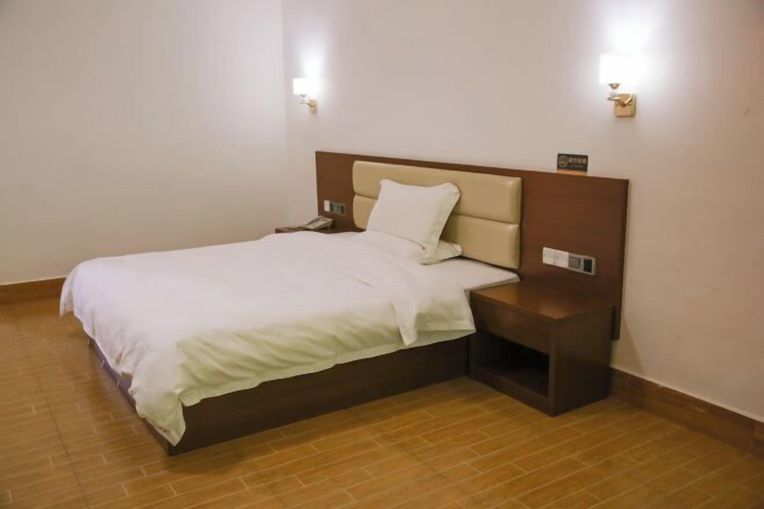A hotel room with a bed, nightstands, and wall-mounted lights.