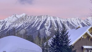 A mountain range with snow-covered peaks and a wooden cabin in the foreground. - Fernie ON THE MOUNTAIN luxury 2 bedrooms 3 beds (1 king, 2 queen), 2 baths.  (Fernie)