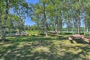 A picnic area with a table and benches, surrounded by trees and a body of water. - Atlanta Waterfront Cabin w/ Dock & Kayaks! (Atlanta)