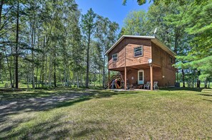 A wooden cabin with a porch, surrounded by a forest. - Atlanta Waterfront Cabin w/ Dock & Kayaks! (Atlanta)