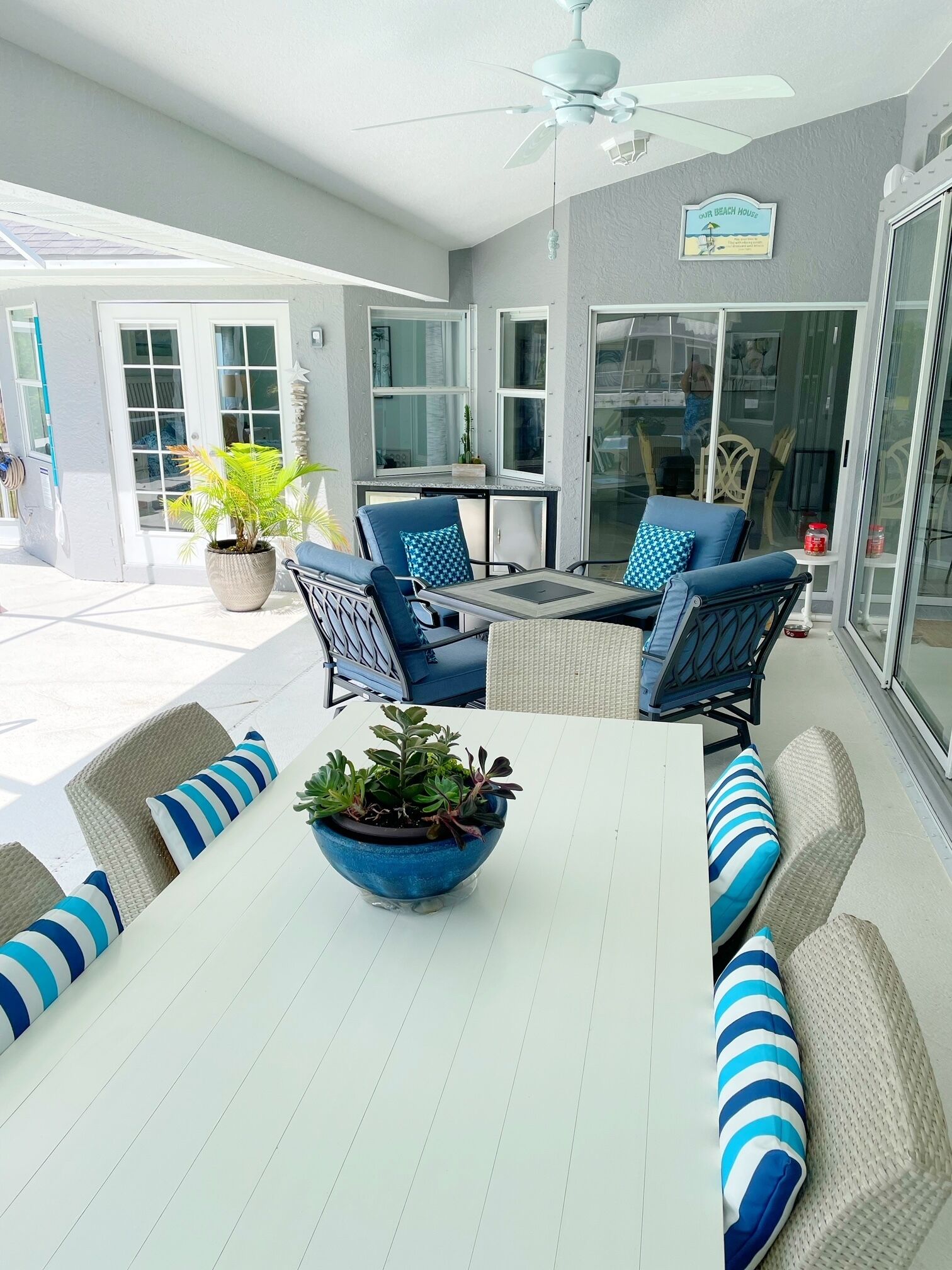 An outdoor patio area with a table, chairs, and a ceiling fan.