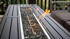A deck with a fire feature, surrounded by a wooden railing and a view of a forested mountain. - Luxury Cabin in the Woods  (Franklin)