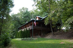 A lodge with a covered porch, stone walls, and a flag.