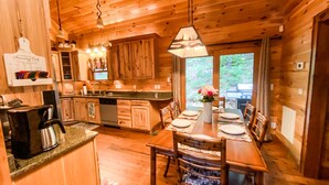 A wooden cabin interior with a kitchen, dining area, and a view of the outdoors. - Luxury Cabin in the Woods  (Franklin)