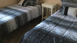 A bedroom with two single beds, a small bedside table, and a wall-mounted picture. - Lake Erie Lily Cabin (Fredonia)